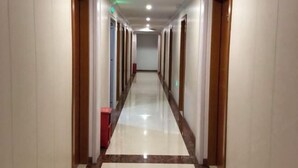 Un pasillo largo y estrecho con puertas a ambos lados que dan a habitaciones individuales.