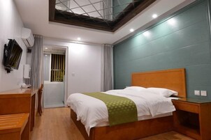 Un dormitorio con una cama de madera, un escritorio, un televisor y un tragaluz.