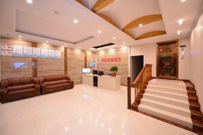 A hotel reception area with a reception desk, seating area, and a staircase. - Tiancheng Jiudian (Zhongjiang)