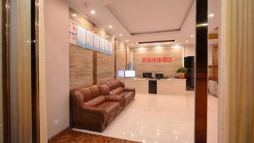 A reception area with a sofa, a reception desk, and a wall-mounted TV.