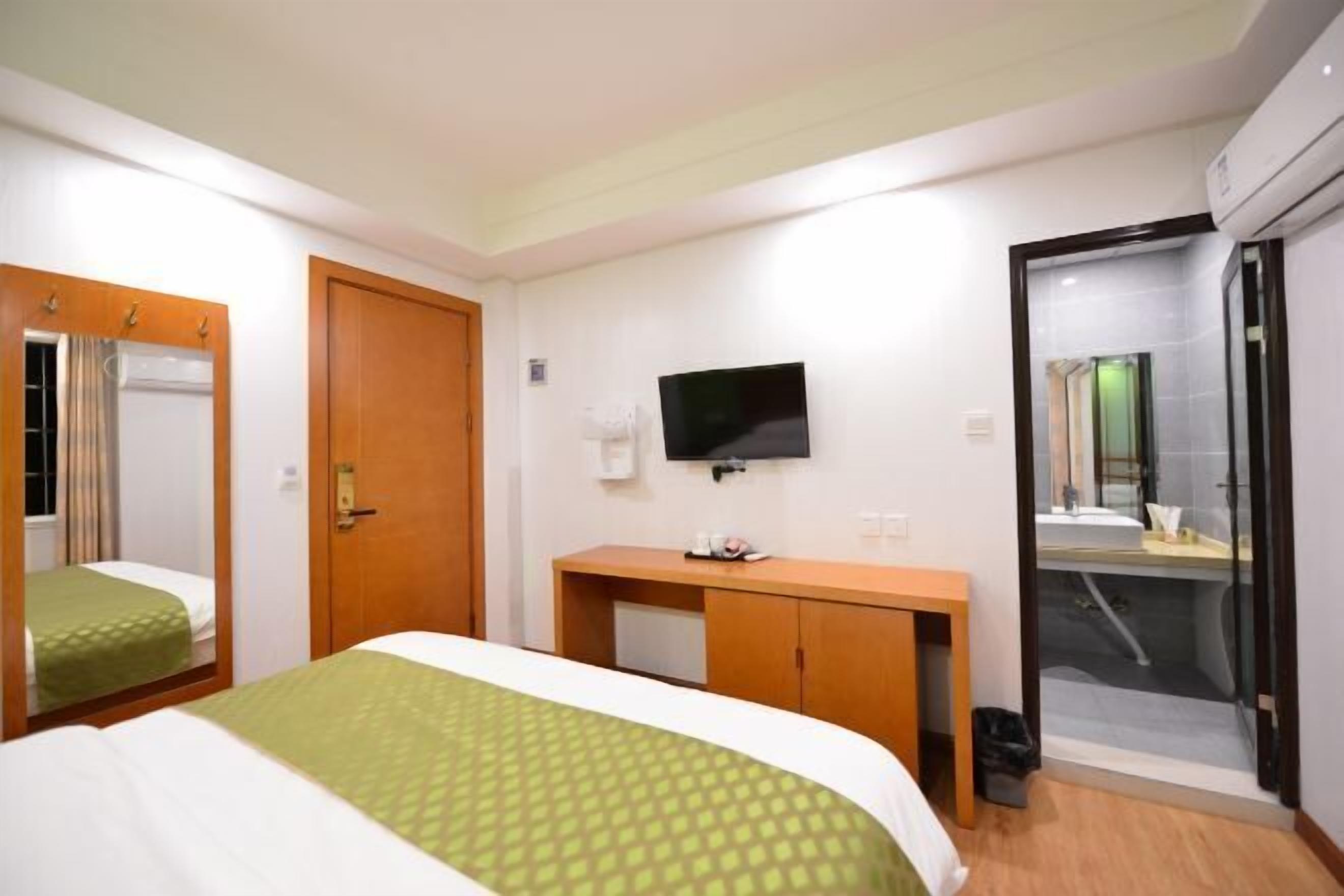 A hotel room with a bed, a desk, a TV, and a bathroom.