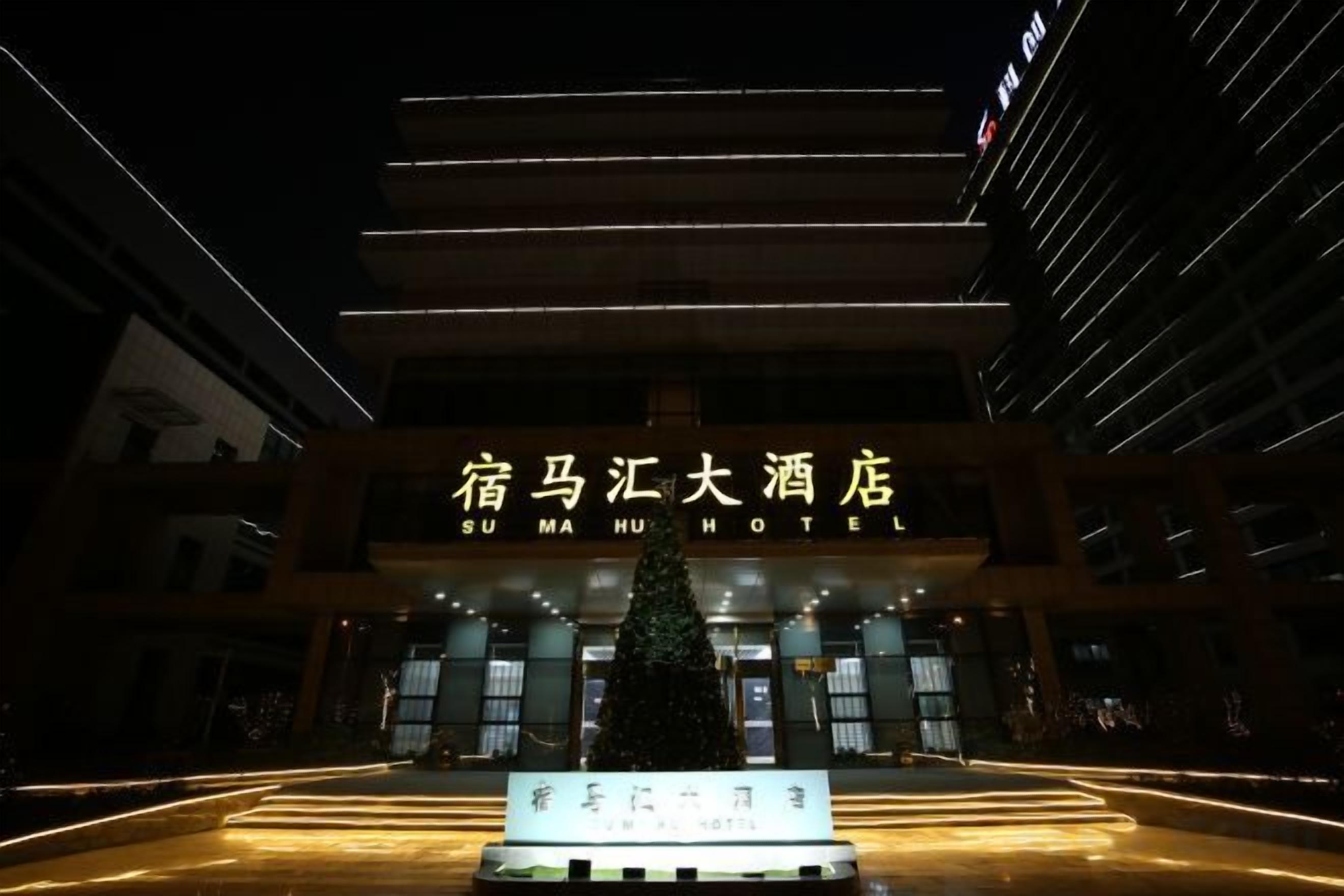 A hotel entrance with illuminated signage and a Christmas tree.