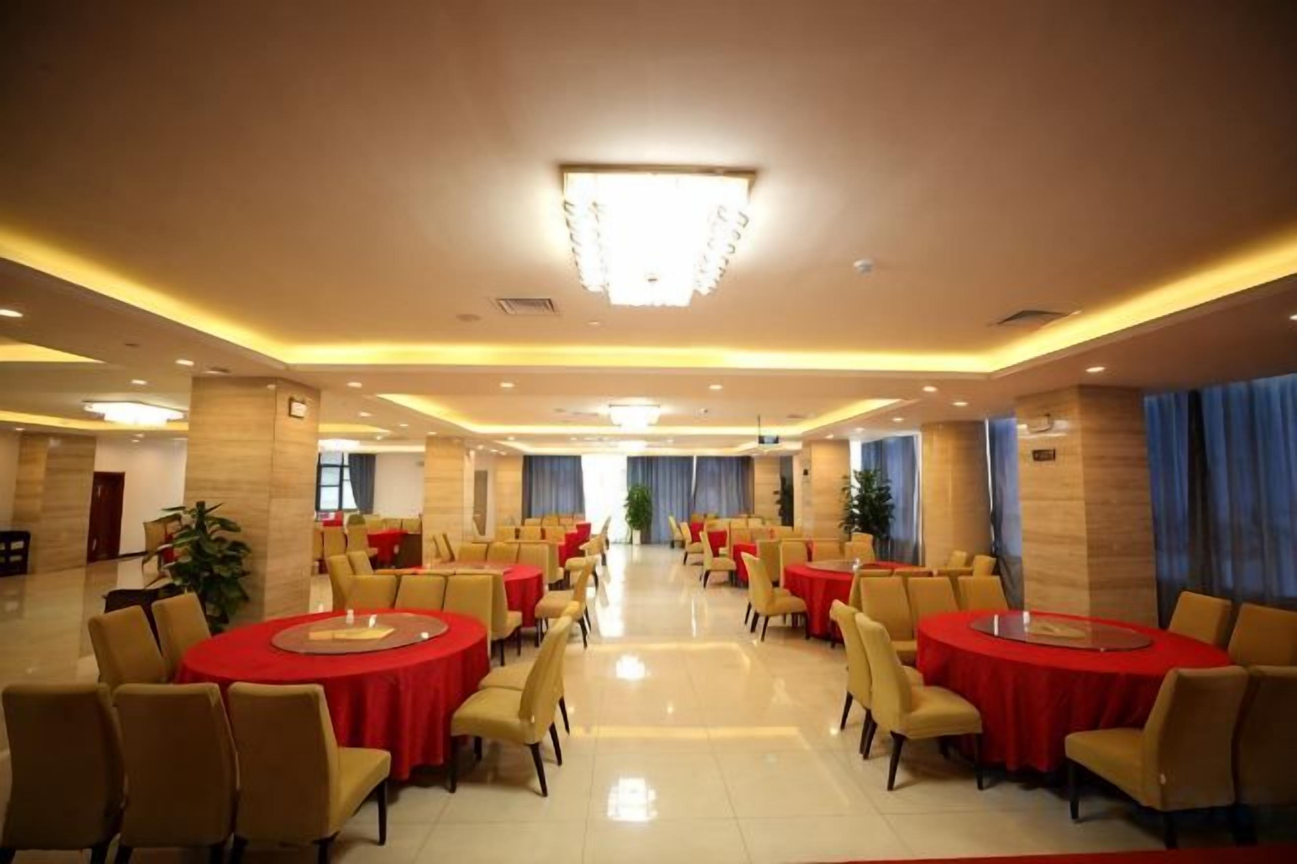 A spacious banquet hall with round tables and chairs, a chandelier, and a clean, polished floor.