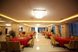 Un amplio salón de banquetes con mesas redondas y sillas, un candelabro y un piso limpio y pulido.