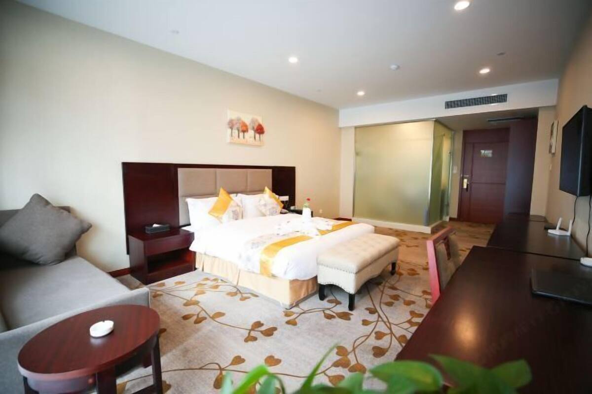 A hotel room with a bed, a sofa, a desk, and a TV.