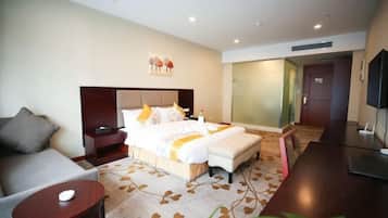 Una habitación de hotel con cama, sofá, escritorio y televisor.
