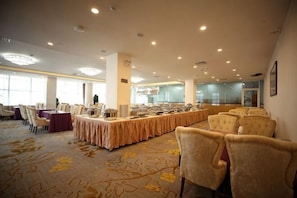Une salle de banquet avec une longue table, des chaises et un sol recouvert de moquette.