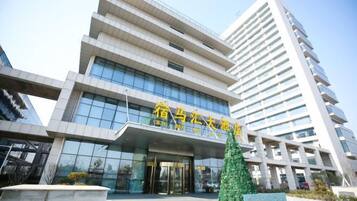 A modern building with a prominent entrance and a tall adjacent structure.