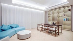 Una sala de estar moderna con un sofá azul, una mesa de centro redonda y una zona de comedor con una mesa y sillas de madera.