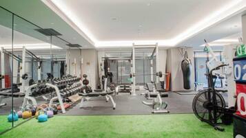 Ein Fitnessraum mit unterschiedlichen Trainingsgeräten, darunter Kurzhanteln, Kettlebells und ein Ergometer.