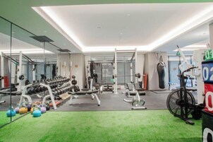 Un gimnasio con diverso equipo de ejercicio, incluyendo mancuernas, balones con peso y una bicicleta estática.