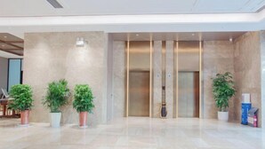 Un vestíbulo amplio con piso de mármol, un mostrador de recepción y un moderno ascensor.