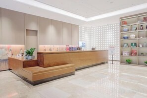 A modern reception area with a wooden reception desk, a seating area, and a decorative wall with shelves.