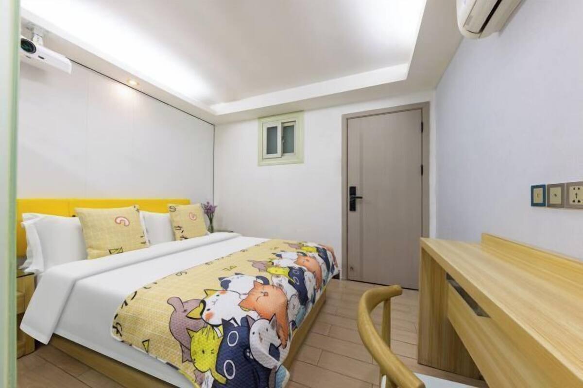 A bedroom with a bed, bedside table, and a small window.