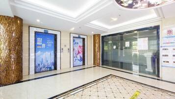 A hotel lobby with a polished floor, a reception desk, and two elevators.
