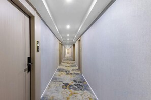 A hotel corridor with doors on both sides, a patterned carpet, and a ceiling with recessed lighting. - Shiman Art Hotel (Guangzhou Chebei Subway Station) (Guangzhou)