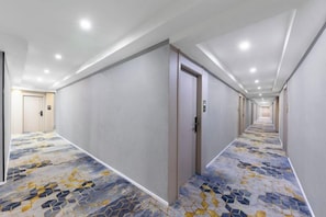 A hotel corridor with a patterned carpet, doors, and recessed lighting. - Shiman Art Hotel (Guangzhou Chebei Subway Station) (Guangzhou)
