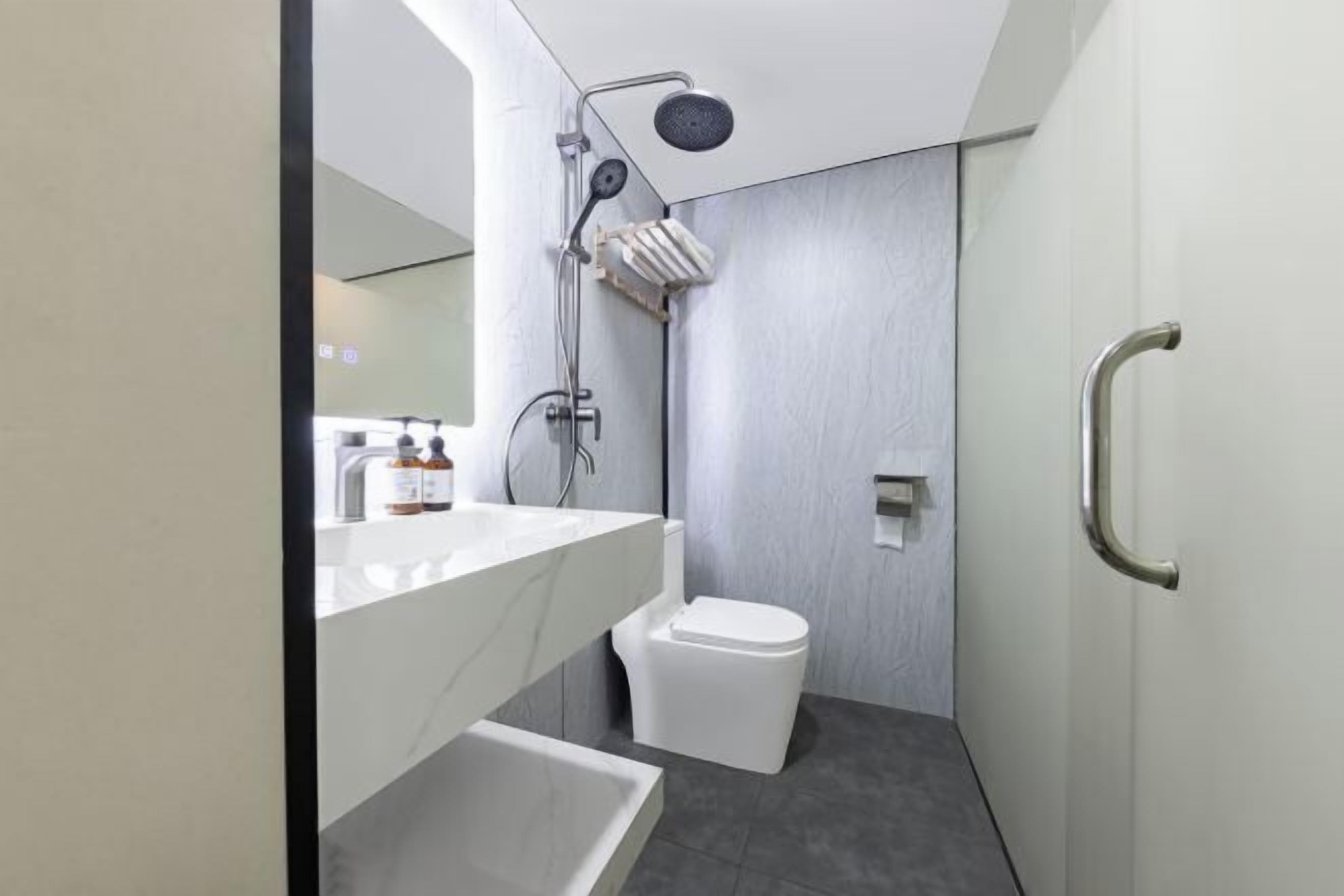 Un baño moderno con lavamanos, espejo y retrete blancos.