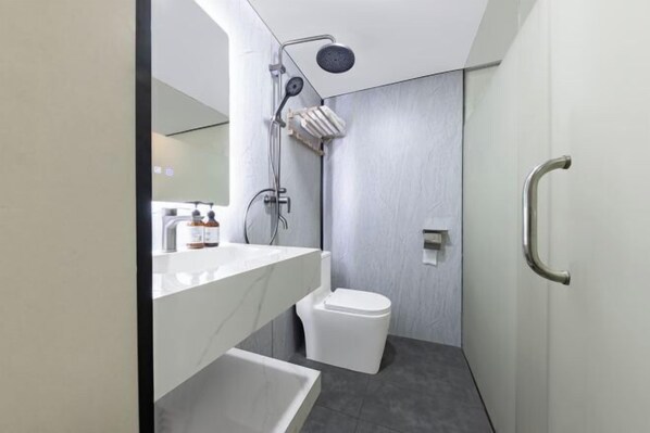 Un baño moderno con lavamanos, espejo y retrete blancos.