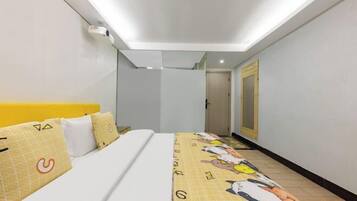 A hotel room with a bed, a headboard, a bedside table, a mirror, and a door.