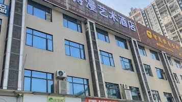 Un edificio de varios pisos con letreros que indican un hotel y varios comercios.