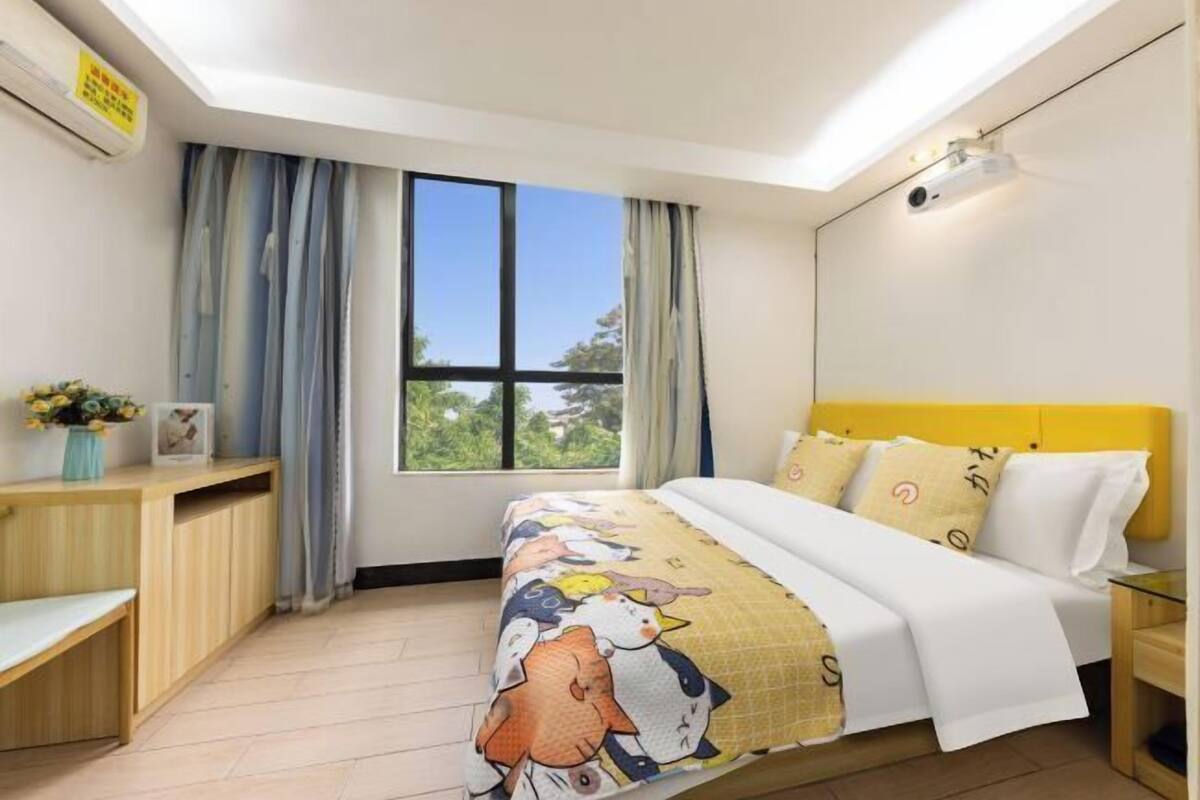 A bedroom with a bed, a desk, a chair, a nightstand, and a window with curtains.