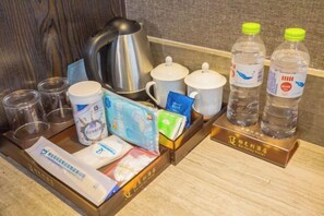 A tray with a kettle, cups, bottles, and various toiletries.