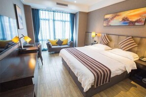 Moderni hotellihuone, jossa on suuri sänky, sohva ja työpöytä.