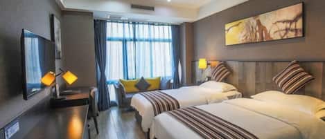Habitación de hotel con dos camas, un escritorio, un televisor y un ventanal con cortinas.