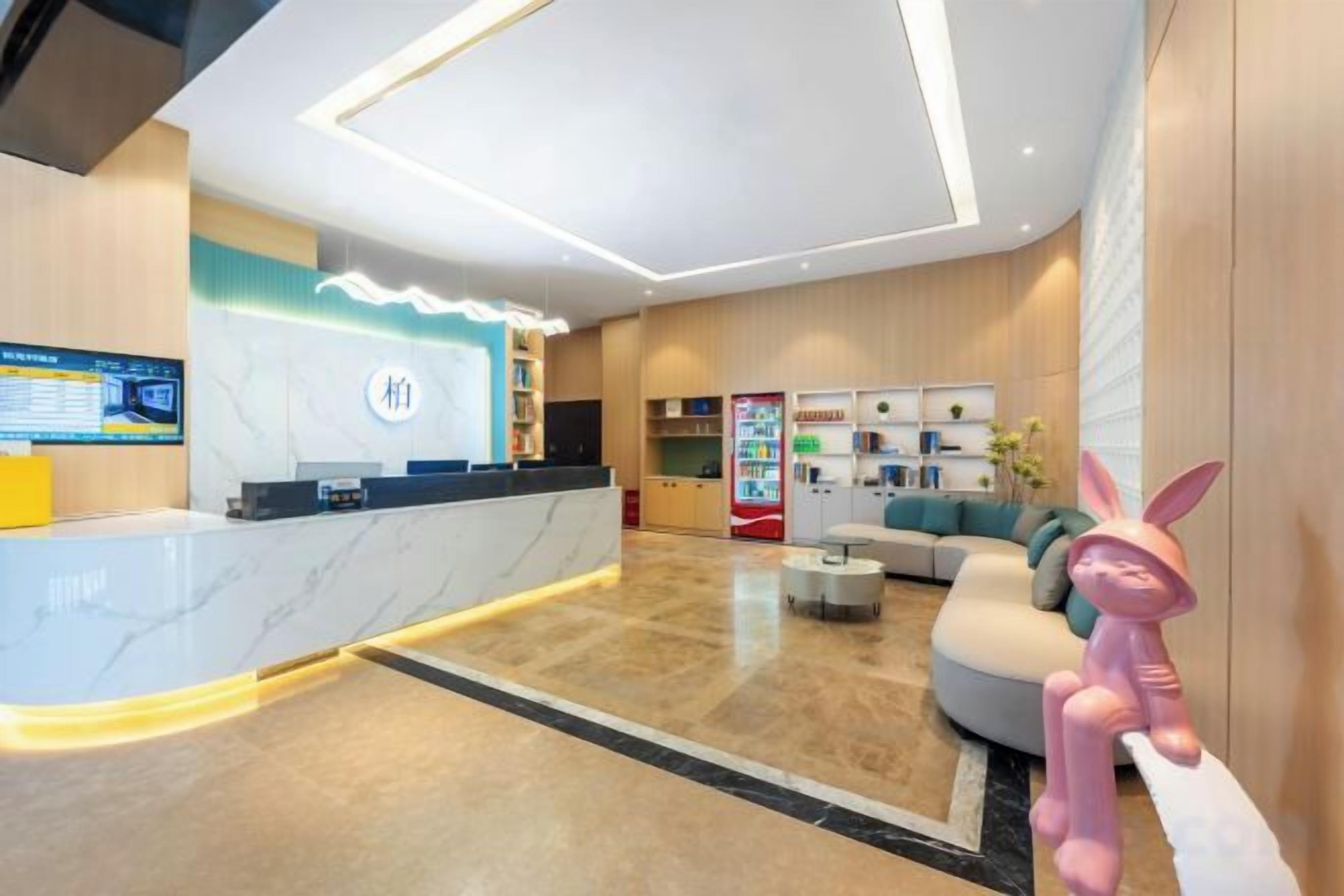 Un moderno vestíbulo de hotel con mostrador de recepción, zona de estar y máquinas expendedoras.