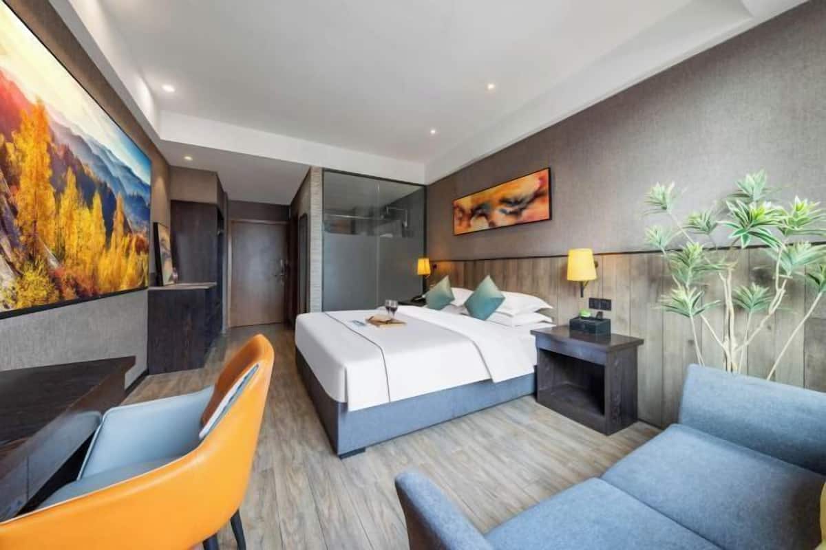 A modern hotel room with a bed, bedside tables, a desk, and a chair.