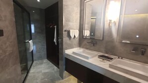 A modern bathroom with a glass shower enclosure, a double sink vanity, and a large mirror. - Railway Grand Hotel (Xiangyang)
