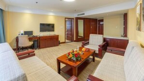A hotel room with a sofa, armchair, desk, TV, and a decorative table. - Railway Grand Hotel (Xiangyang)