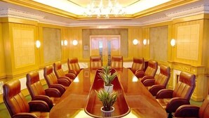A conference room with a long table and leather chairs, a chandelier, and a plant. - Railway Grand Hotel (Xiangyang)