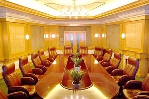 A conference room with a long table and leather chairs, a chandelier, and a plant. - Railway Grand Hotel (Xiangyang)