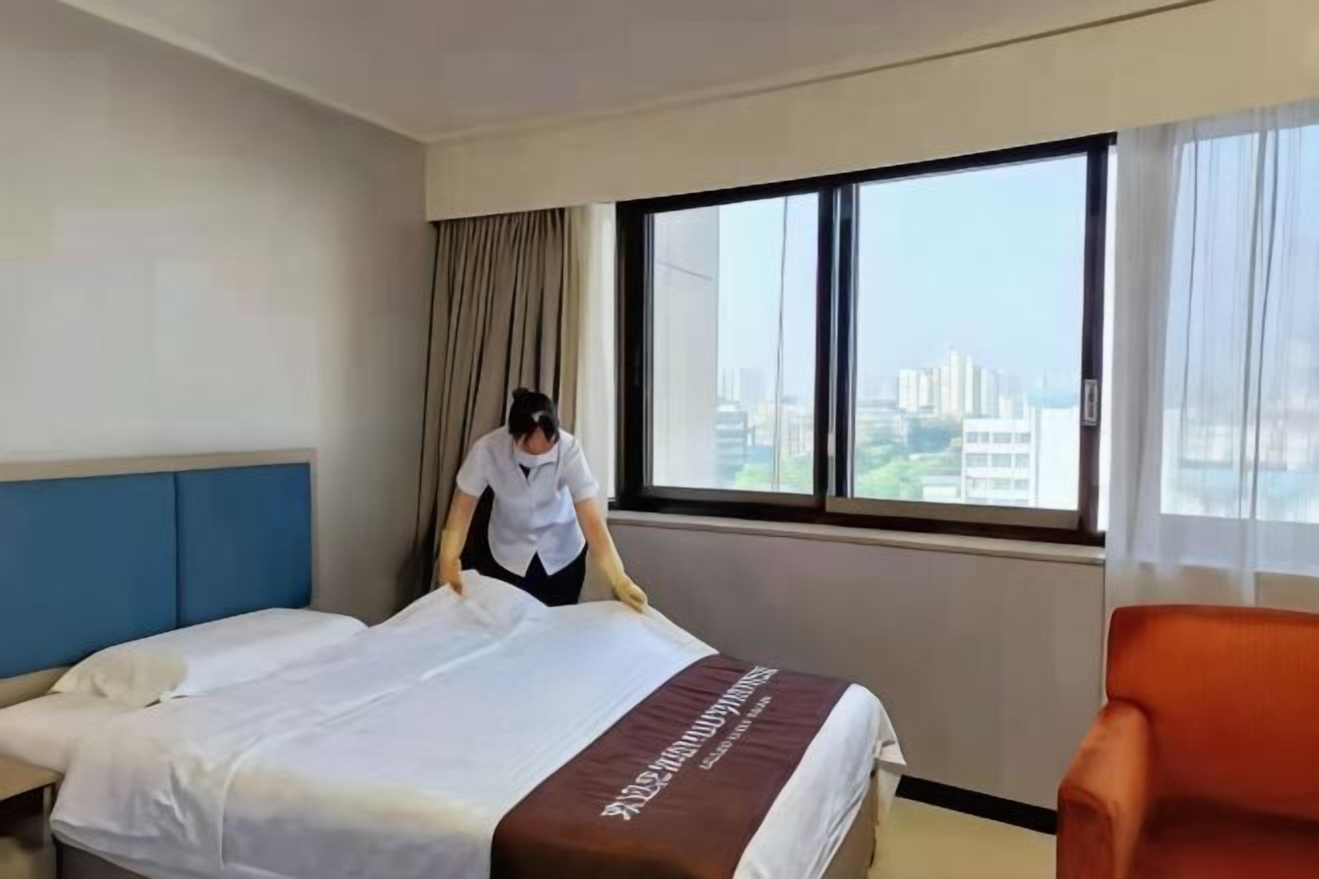 Ein Hotelzimmer mit Bett, Fenster und Blick auf die Stadt.