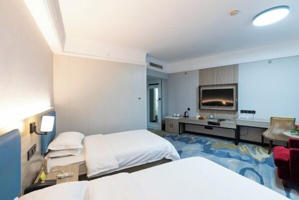 Una habitación de hotel con dos camas, un escritorio, un espejo y una pequeña zona de estar.