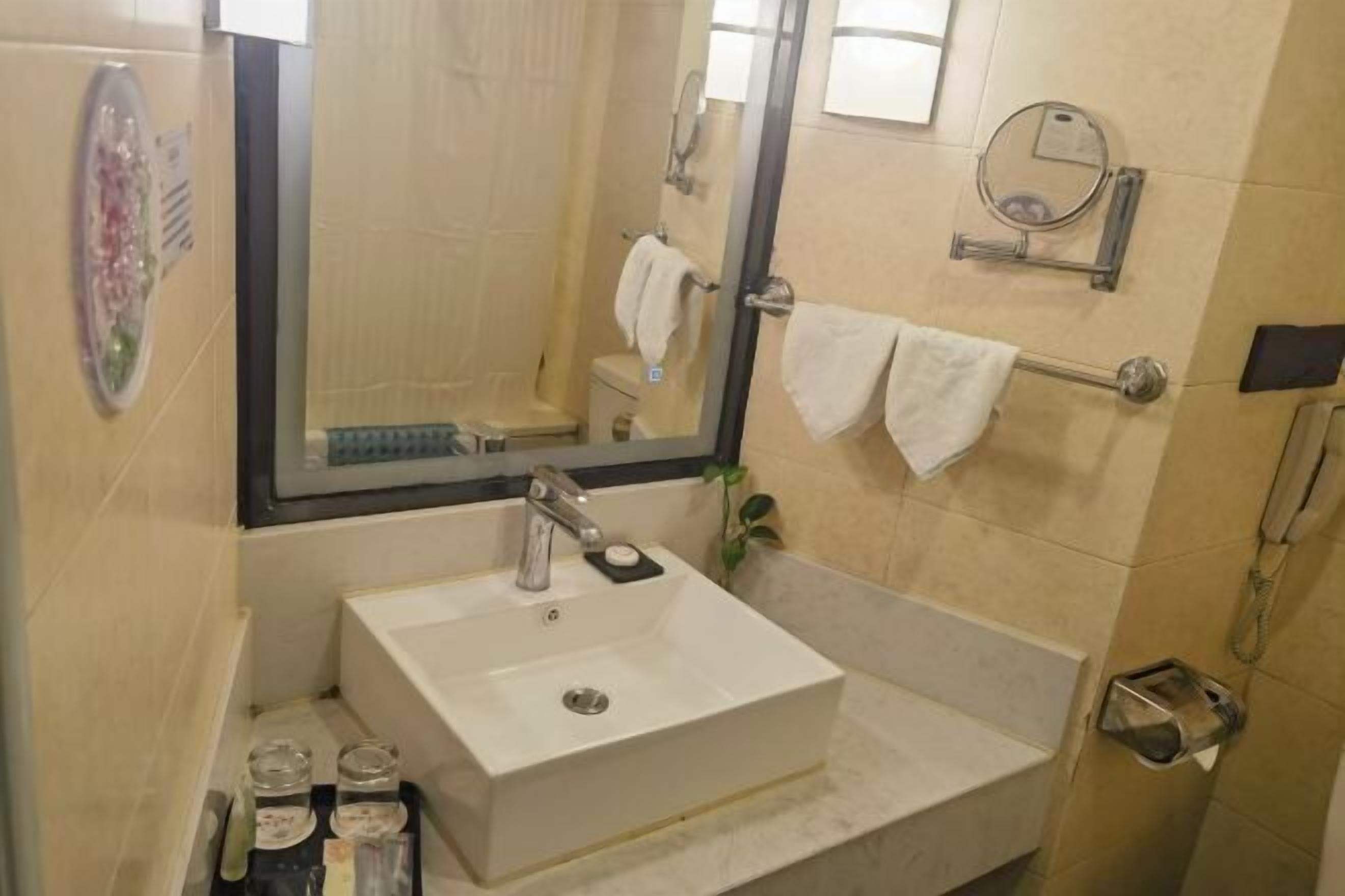 Une salle de bain avec un lavabo blanc, un miroir, un porte-serviettes et un espace douche.