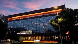 A modern hotel building with a glass facade and illuminated signage. - Gallery Hotel (Zhangjiagang)