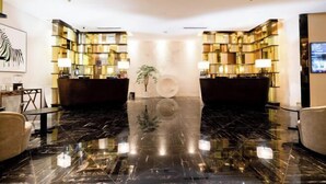 A lobby with a marble floor, a reception desk, and a large abstract art piece on the wall. - Gallery Hotel (Zhangjiagang)