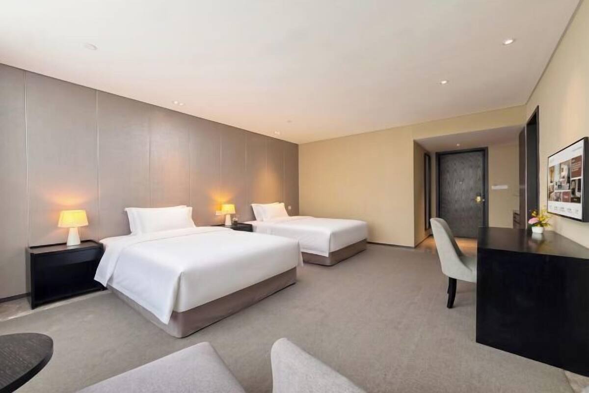Hotellihuone, jossa on kaksi sänkyä, työpöytä ja tuoli.