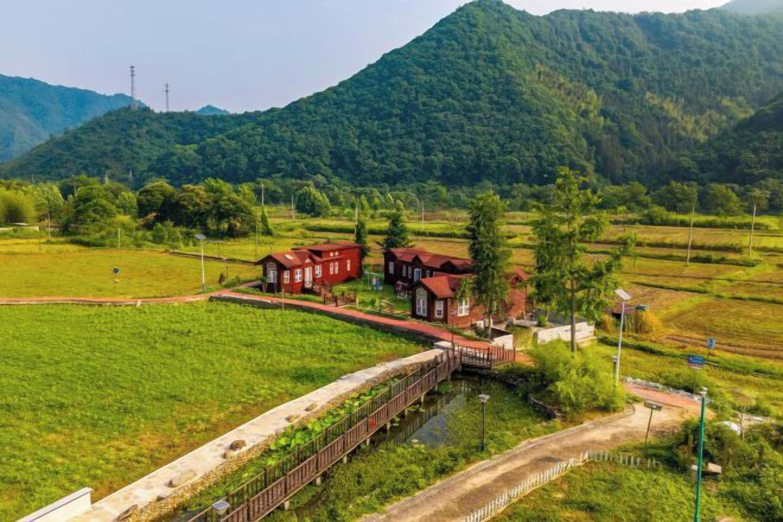 Paisaje rural con un puente, campos y un grupo de construcciones tradicionales.