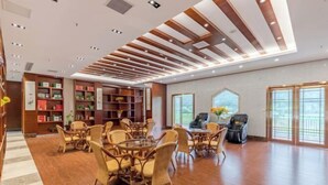 Un lobby espacioso con piso de madera, muebles de mimbre y un diseño moderno en el techo.