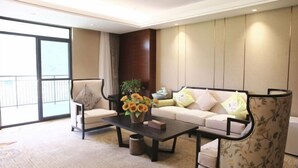 Una sala de estar moderna con un sofá, sillones, una mesa de centro y un ventanal grande.