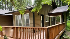 Une cabane dotée d’une terrasse en bois, de grandes fenêtres et d’une porte.