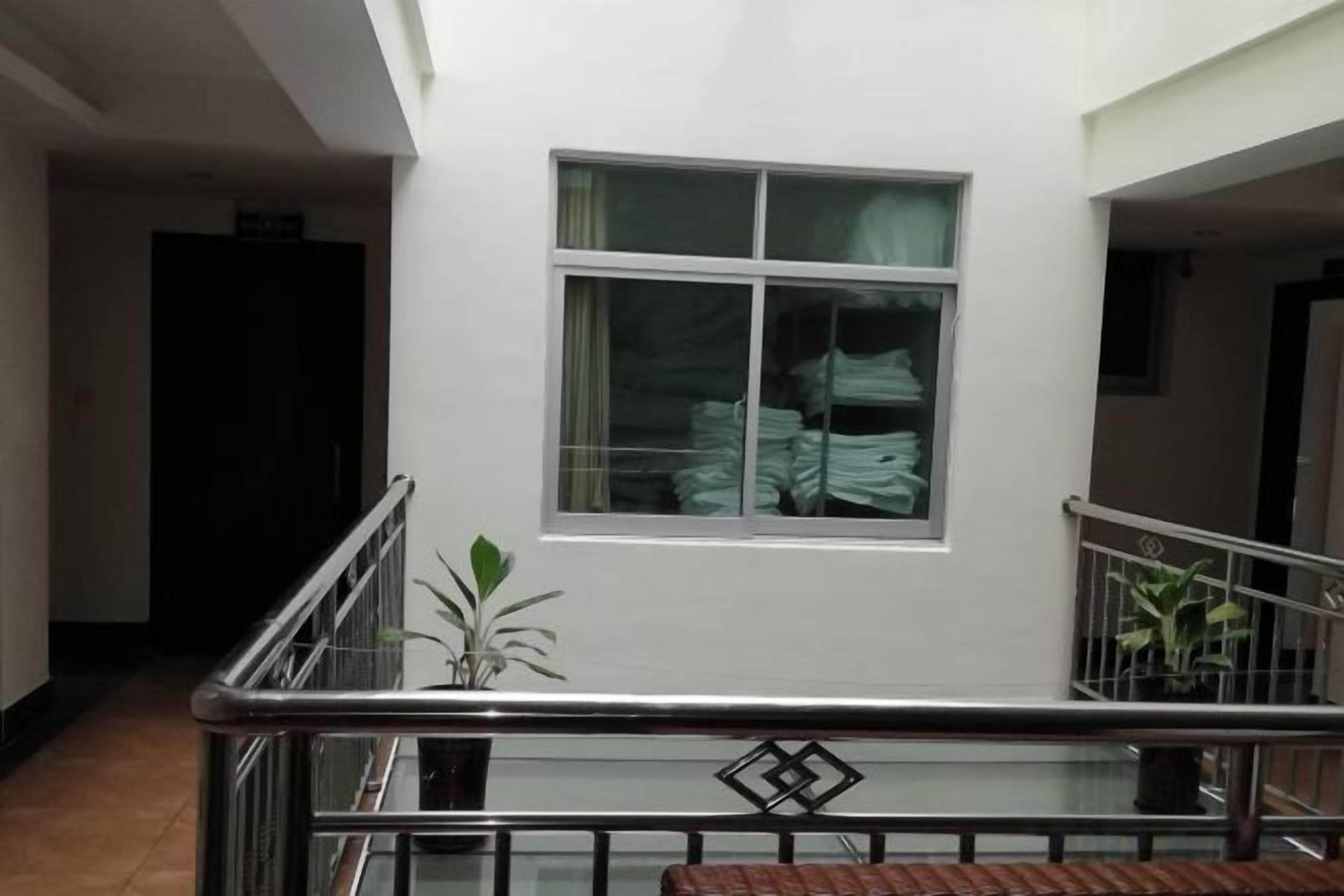 A hotel interior with a staircase, a window with curtains, and a railing.
