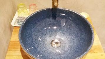 A round, dark blue ceramic sink with a brass faucet on a wooden surface.