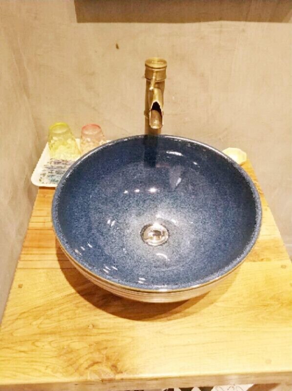 A round, dark blue ceramic sink with a brass faucet on a wooden surface. - Wenchang Haiju Diary Homestay (Wenchang)