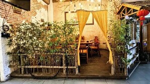A rustic interior with exposed brick walls, a wooden table, and a canopy. - Wenchang Haiju Diary Homestay (Wenchang)