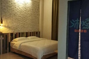 Una habitación con pared de ladrillos, una cama de madera y una cortina con texto.